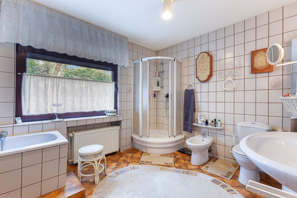 Helles Badezimmer mit Dusche, Badewanne, WC, Bidet, Waschbecken und großem Fenster.