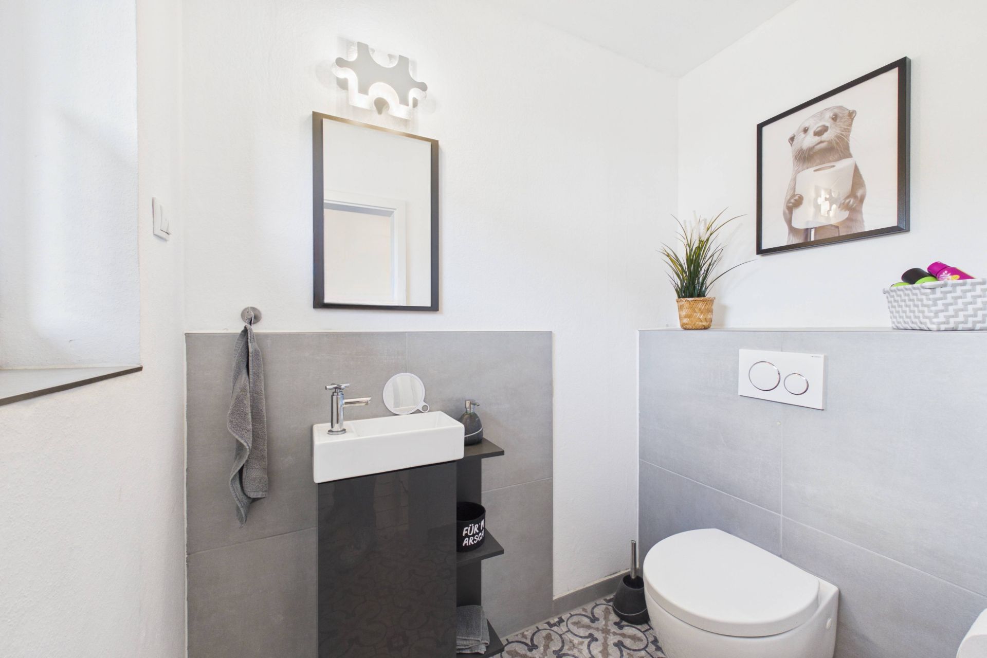 Modernes Badezimmer mit Waschbecken, Spiegel, Toilette und dekorativen Elementen.