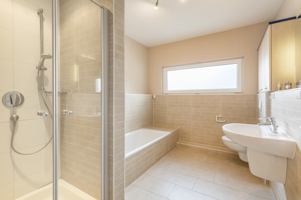 Modernes Badezimmer mit Dusche, Badewanne, Waschbecken und Fenster.