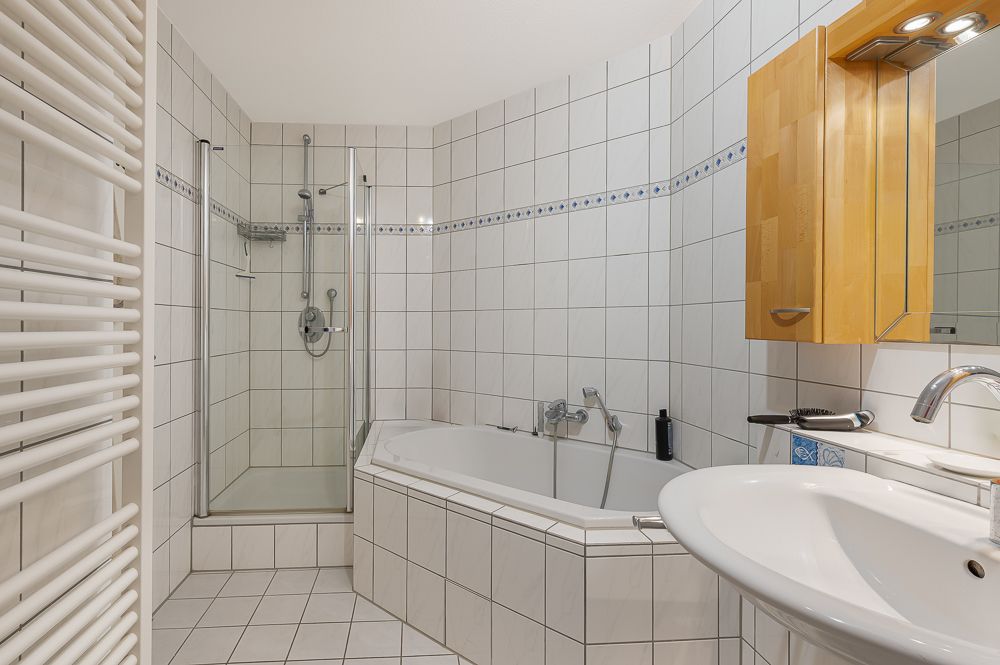 Helles Badezimmer mit Eckbadewanne, Dusche, Waschbecken und Spiegelschrank.