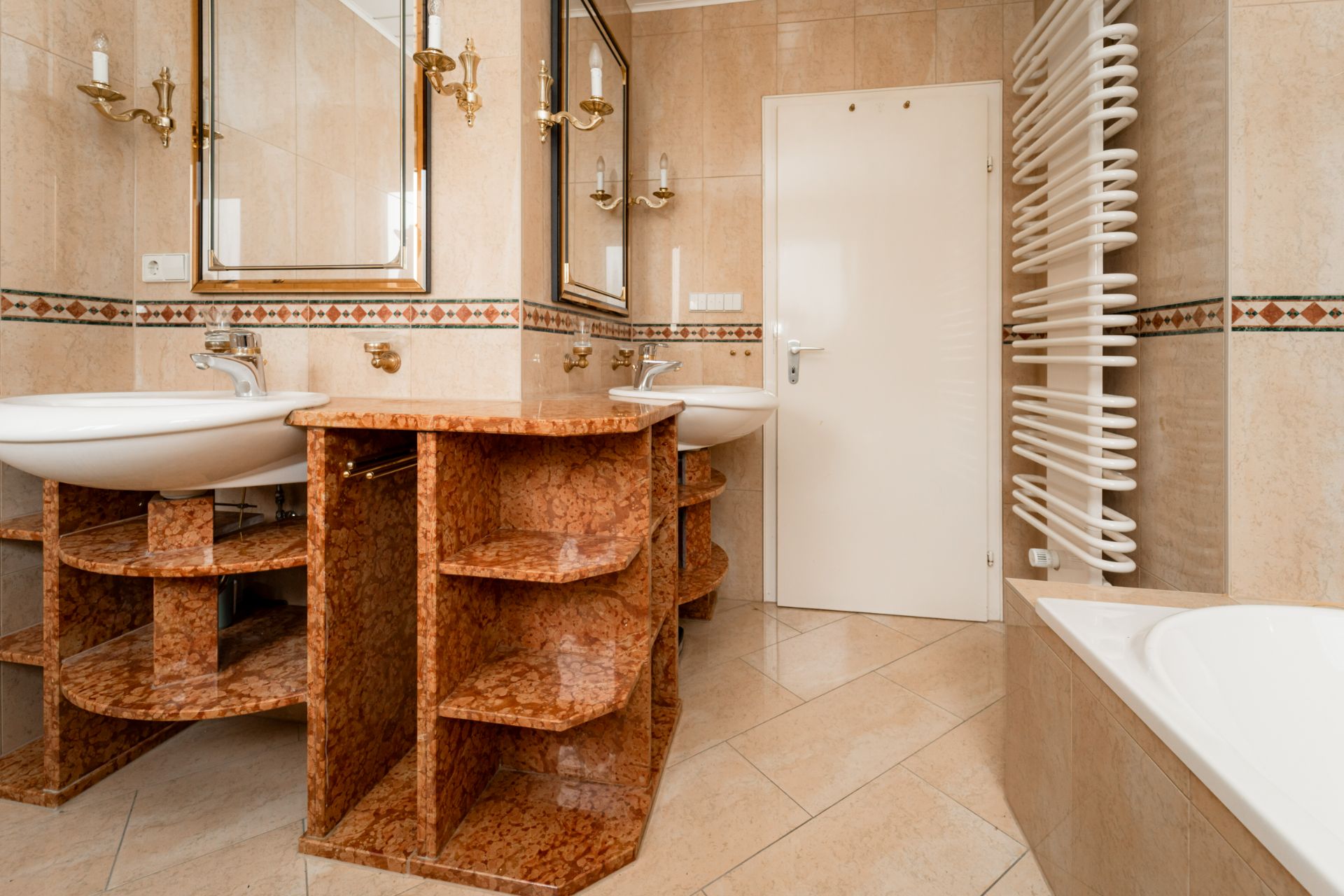 Badezimmer mit zwei Waschbecken, Spiegeln, Regal, Badewanne und Handtuchheizkörper.
