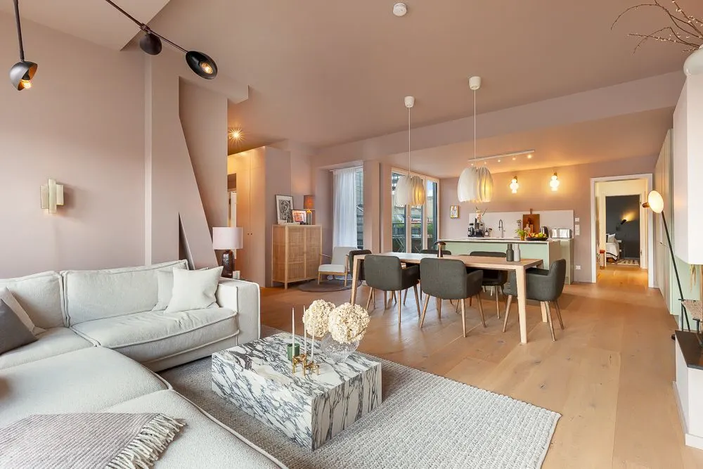 Modernes Wohnzimmer mit Sofa, Couchtisch, Esstisch und offener Küche, helle und gemütliche Einrichtung.