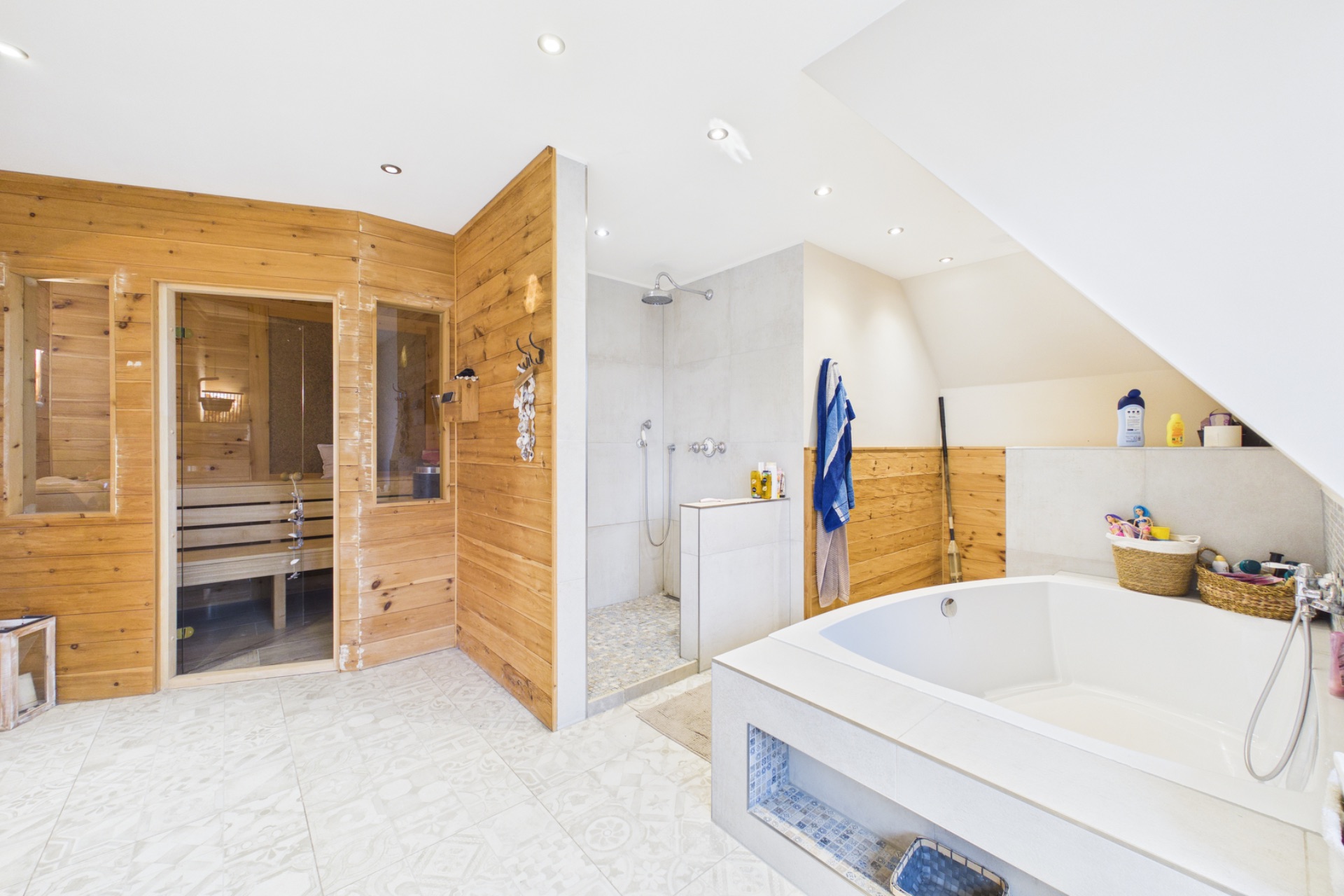 Modernes Badezimmer mit Sauna, begehbarer Dusche und Badewanne unter einer Dachschräge.
