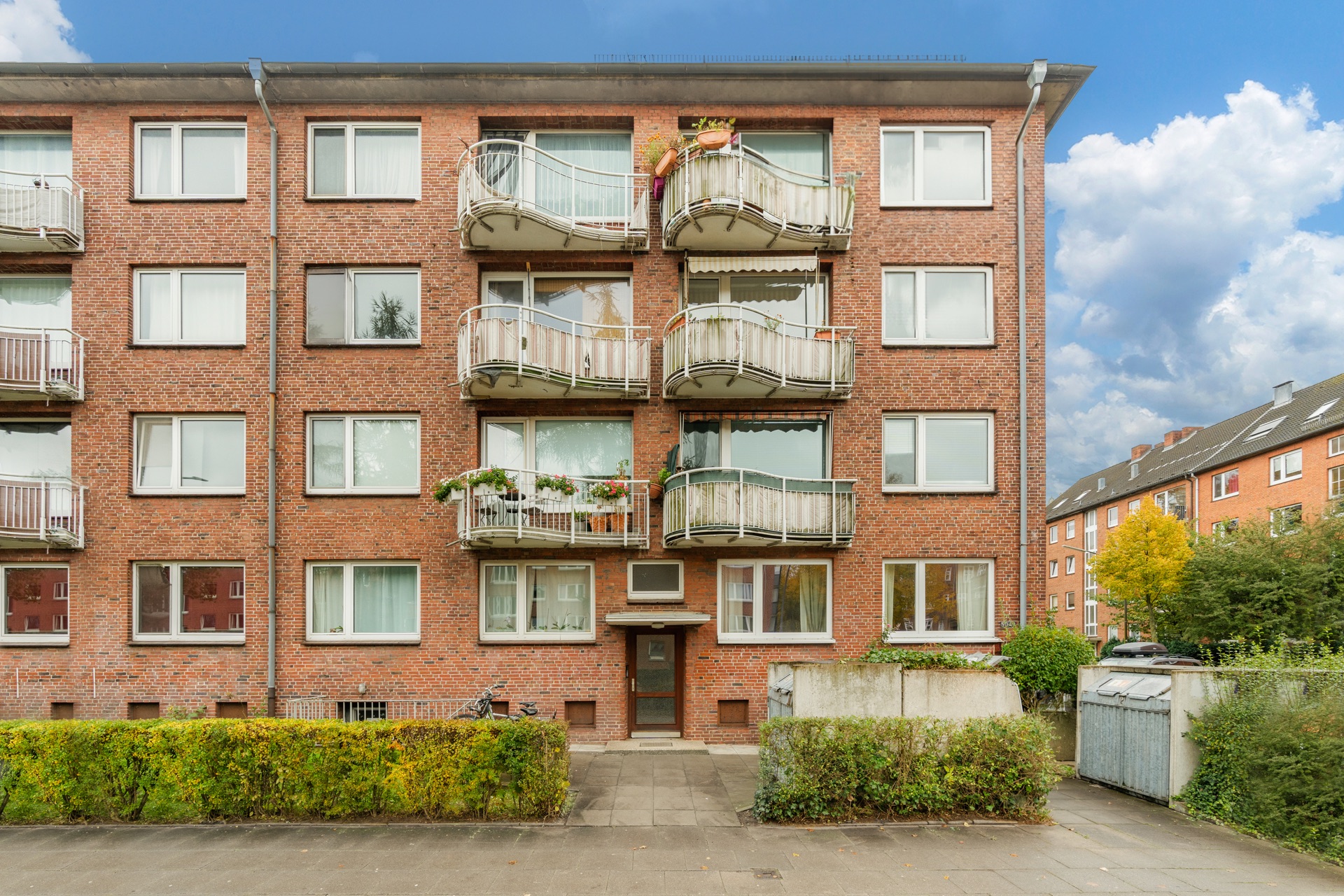 Vierstöckiges Wohnhaus aus rotem Backstein mit Balkonen und großen Fenstern.