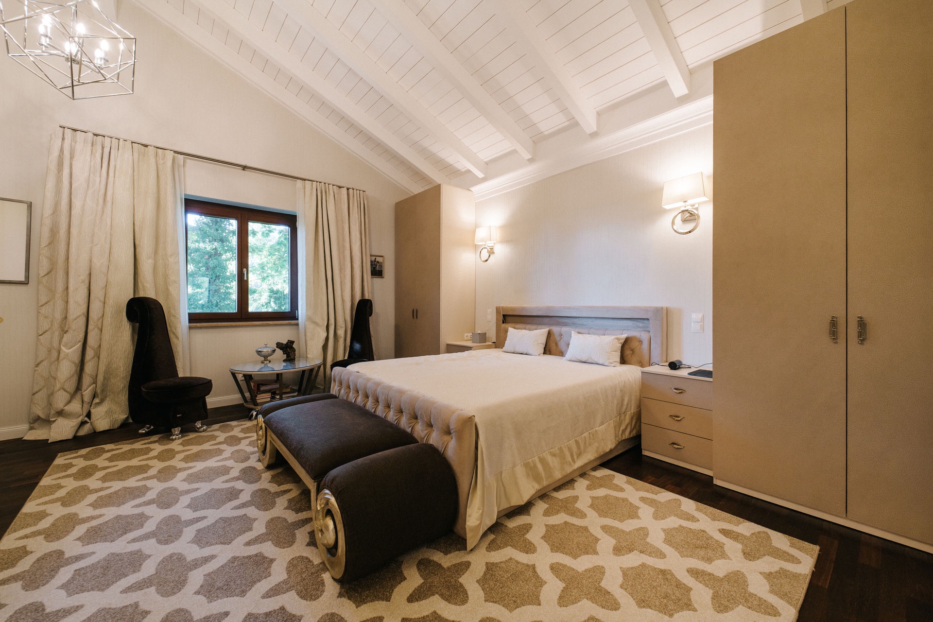 Modernes Schlafzimmer mit Doppelbett, Teppich, Sessel, Fenster und Einbauschränken.