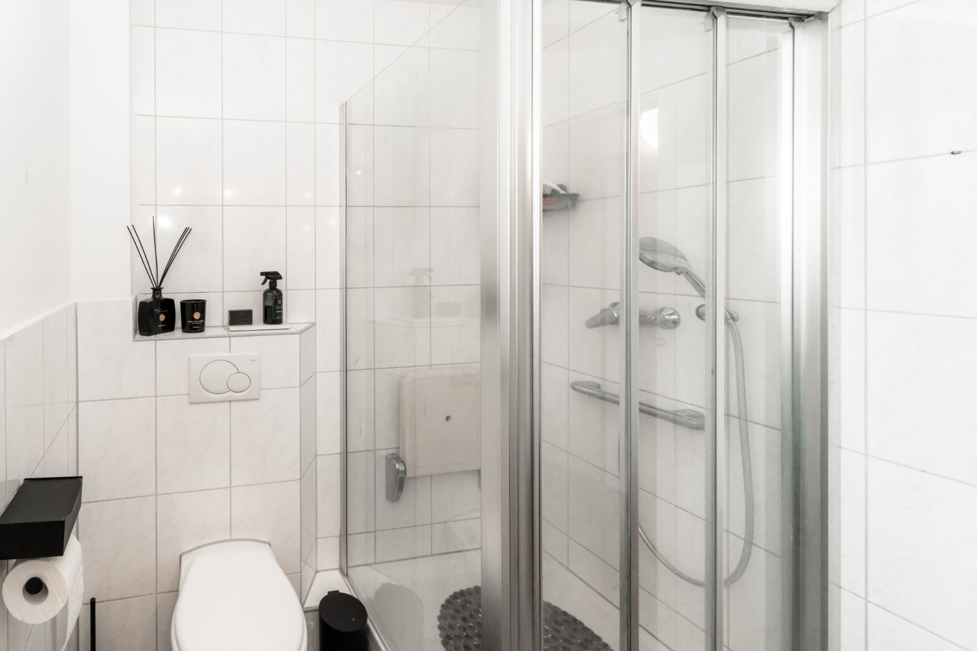 Modernes Bad mit WC, Glasdusche und weißen Fliesen.