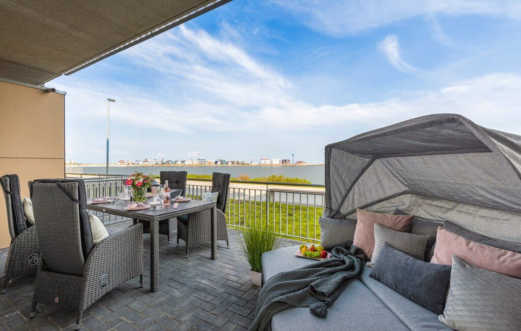 Große Terrasse mit Esstisch, bequemen Stühlen und Sofa, Blick aufs Wasser.