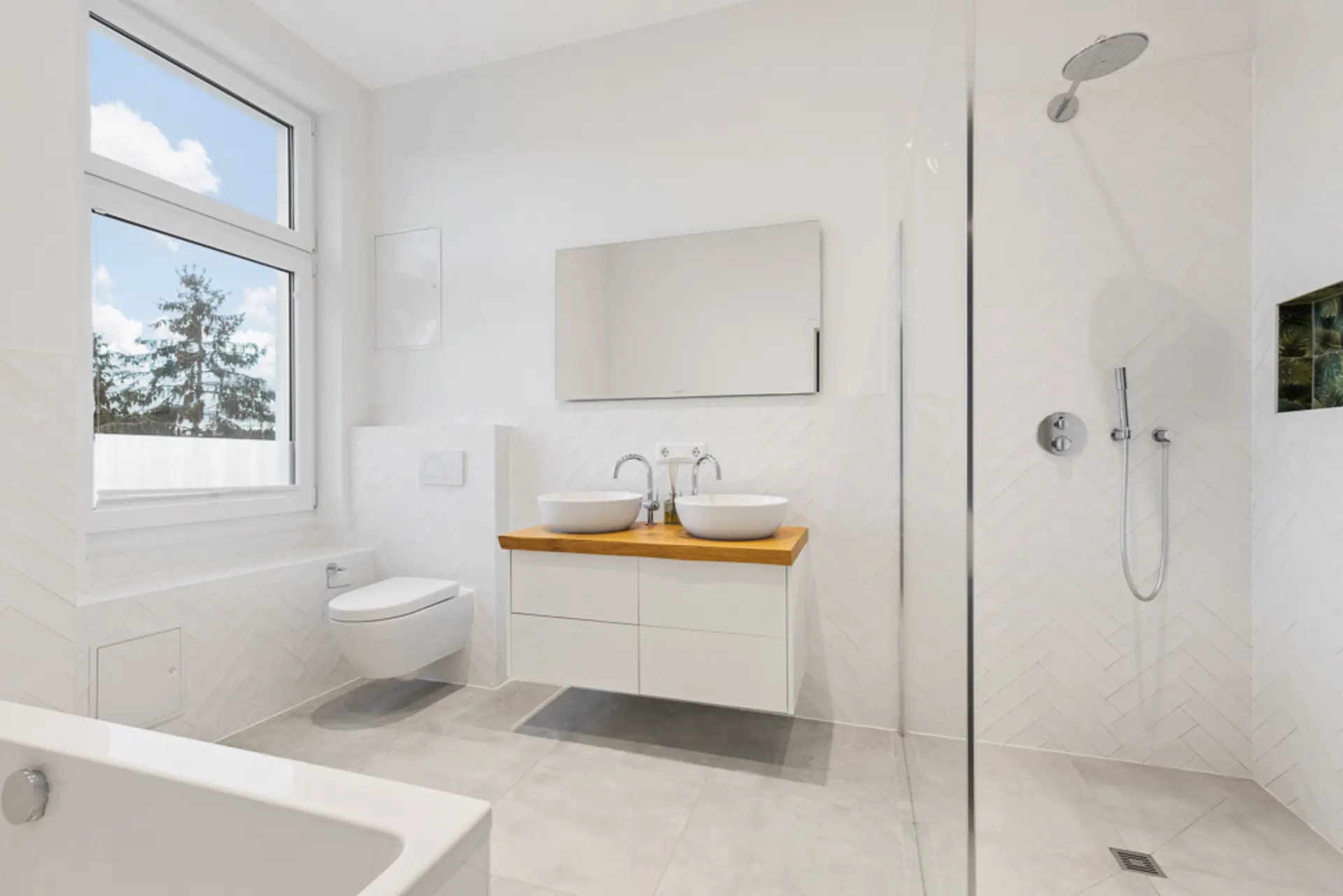 Helles, modernes Badezimmer mit Dusche, Doppelwaschbecken, WC und großer Fensterfront.