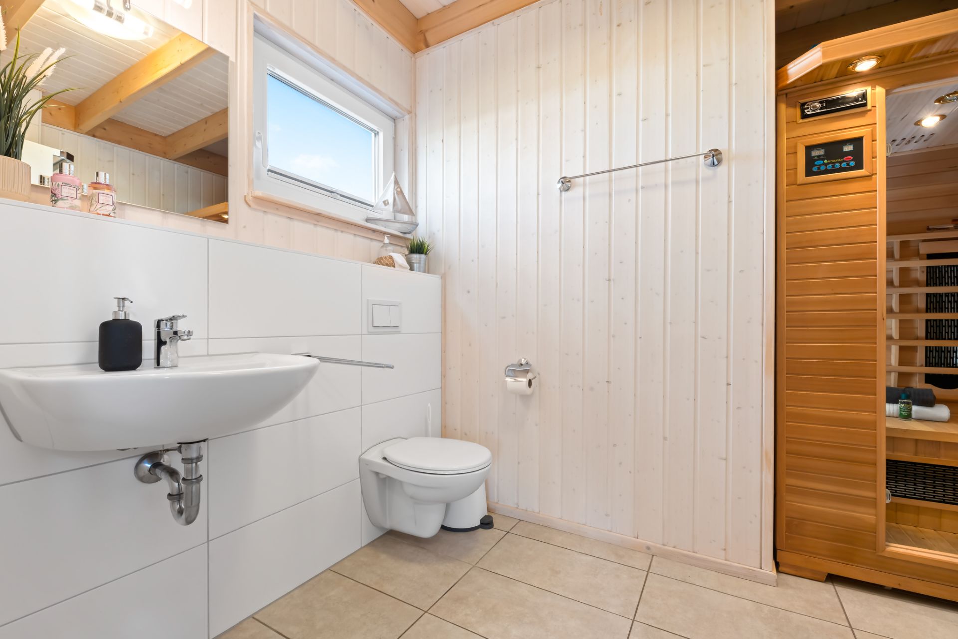 Modernes Badezimmer mit Waschbecken, Toilette und Holzinfrarotsauna.