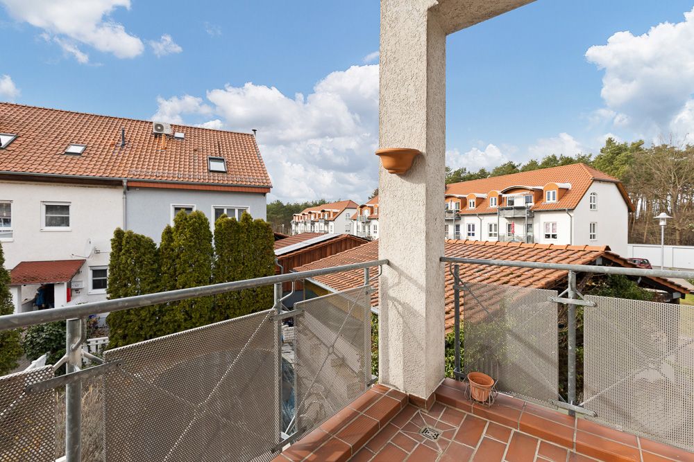 Balkon mit Fliesenboden und Blick auf Wohnhäuser mit roten Dächern bei Tageslicht.