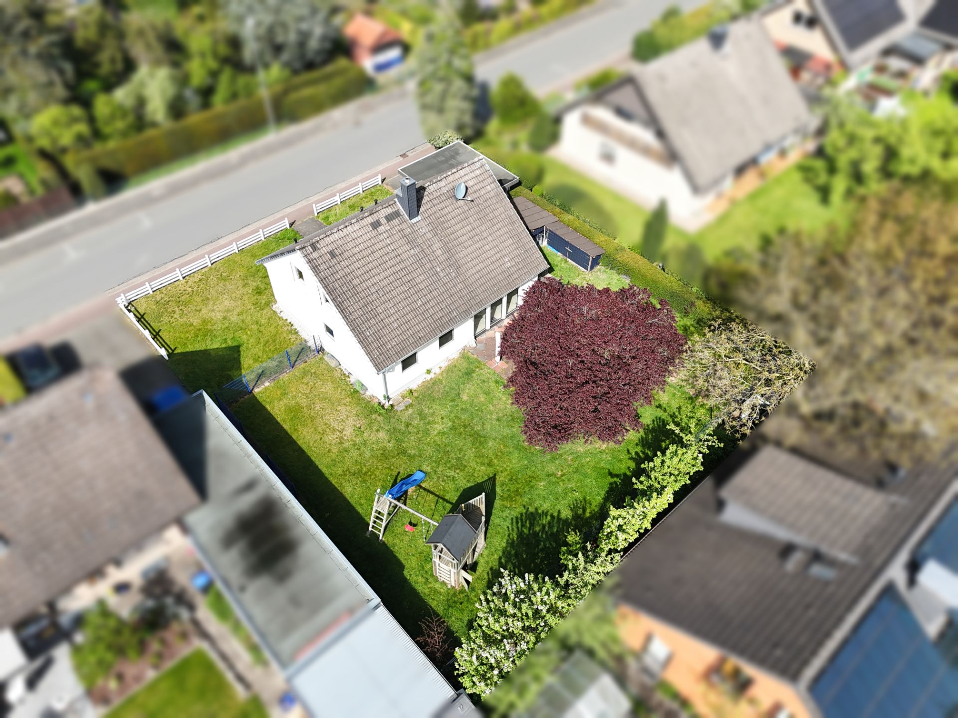 Luftaufnahme eines Einfamilienhauses mit großem Garten und Spielplatz im Hinterhof.