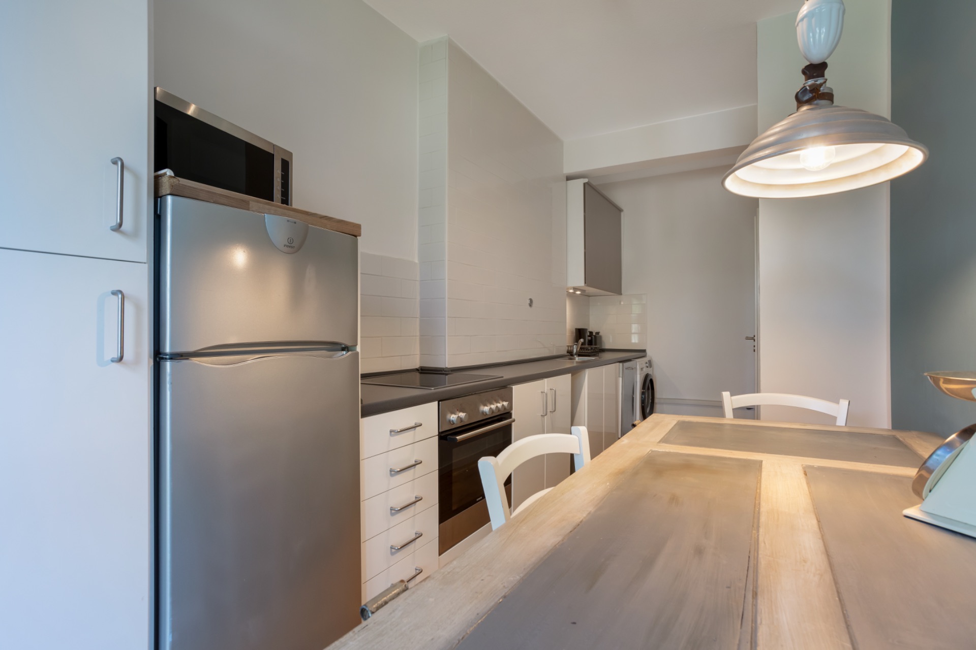 Moderne Küche mit Esstisch, Kühlschrank, Herd und Lampe.