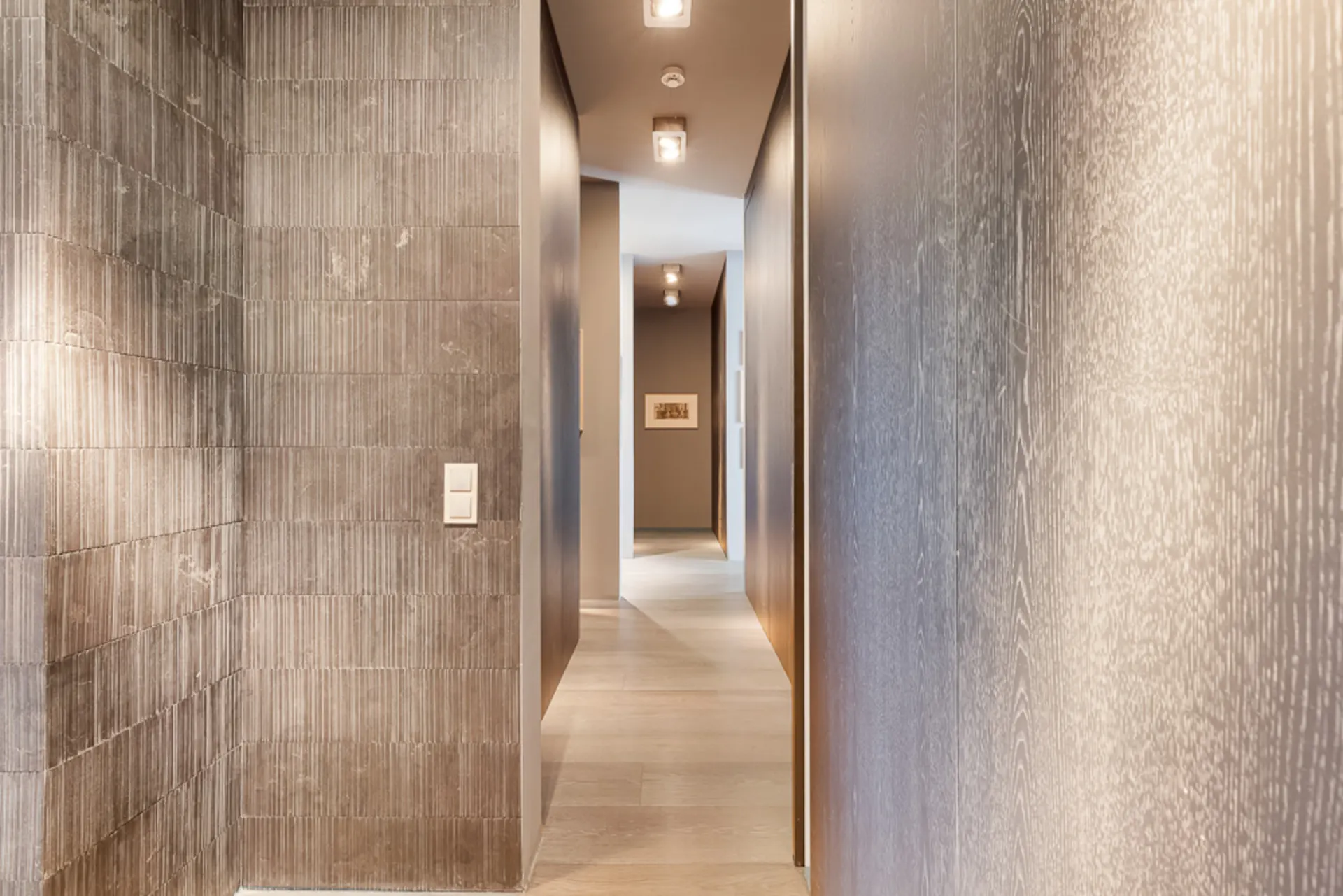 Moderner Flur mit Holzboden, Wandverkleidung und Deckenbeleuchtung.