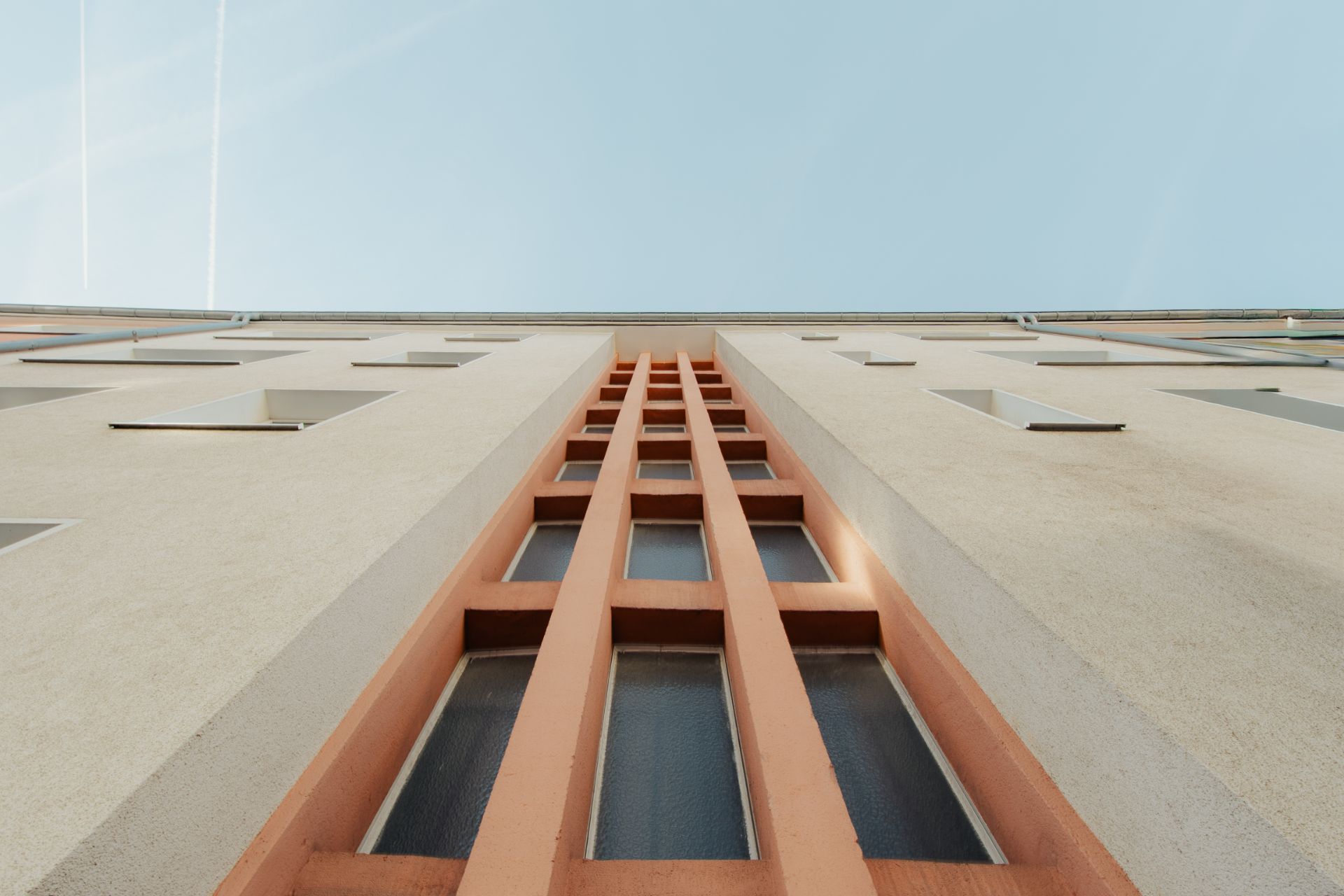 Fassade eines mehrstöckigen Wohngebäudes mit schmalen Fenstern und beigem Putz.