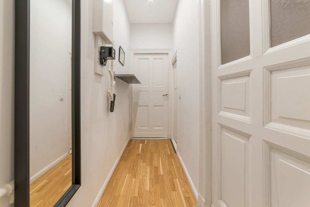Heller Flur mit Holzboden, Spiegel und weißen Türen in einer Wohnung.