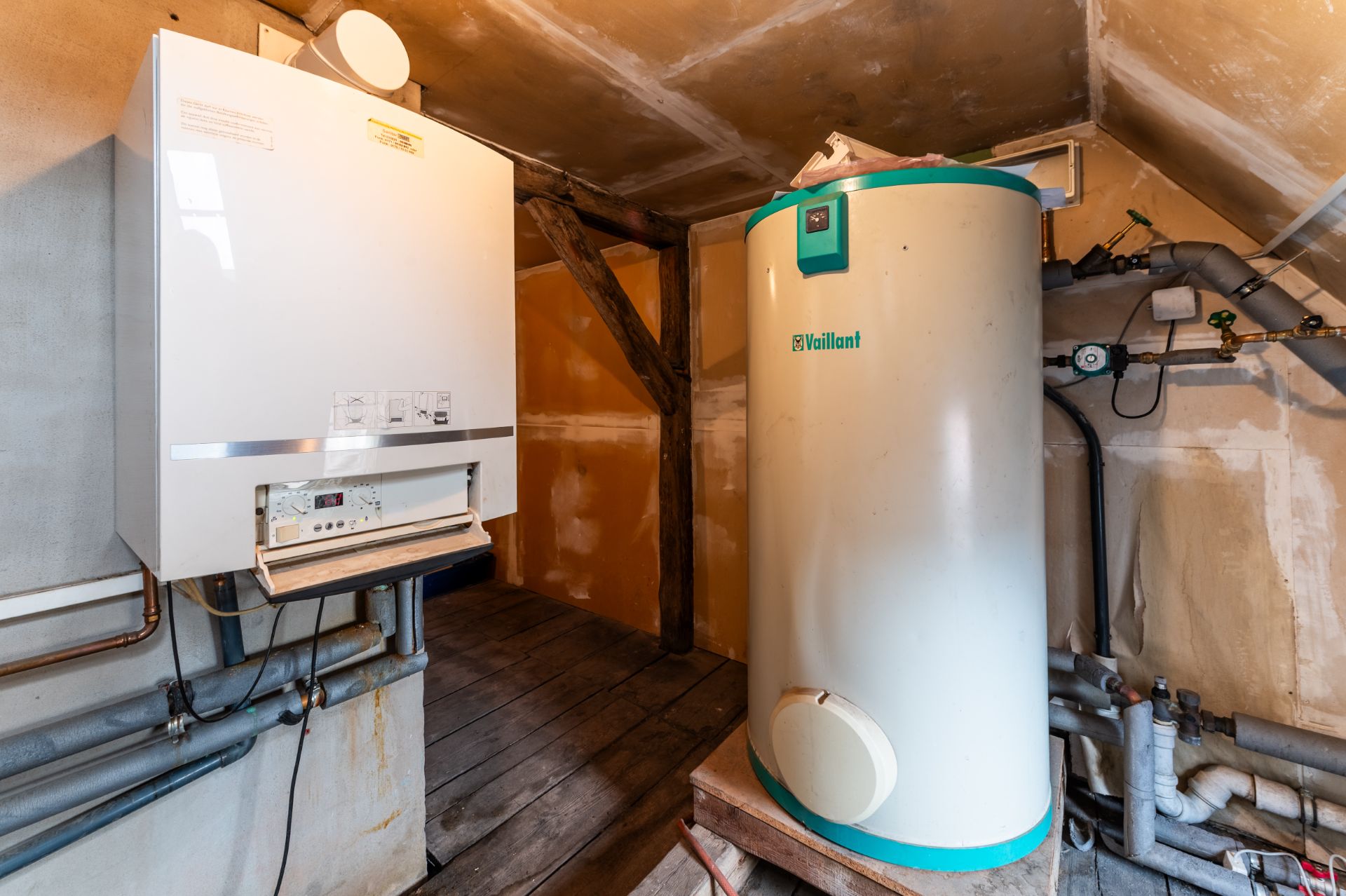 Heizungsraum mit Boiler und Heizkessel auf Holzboden.