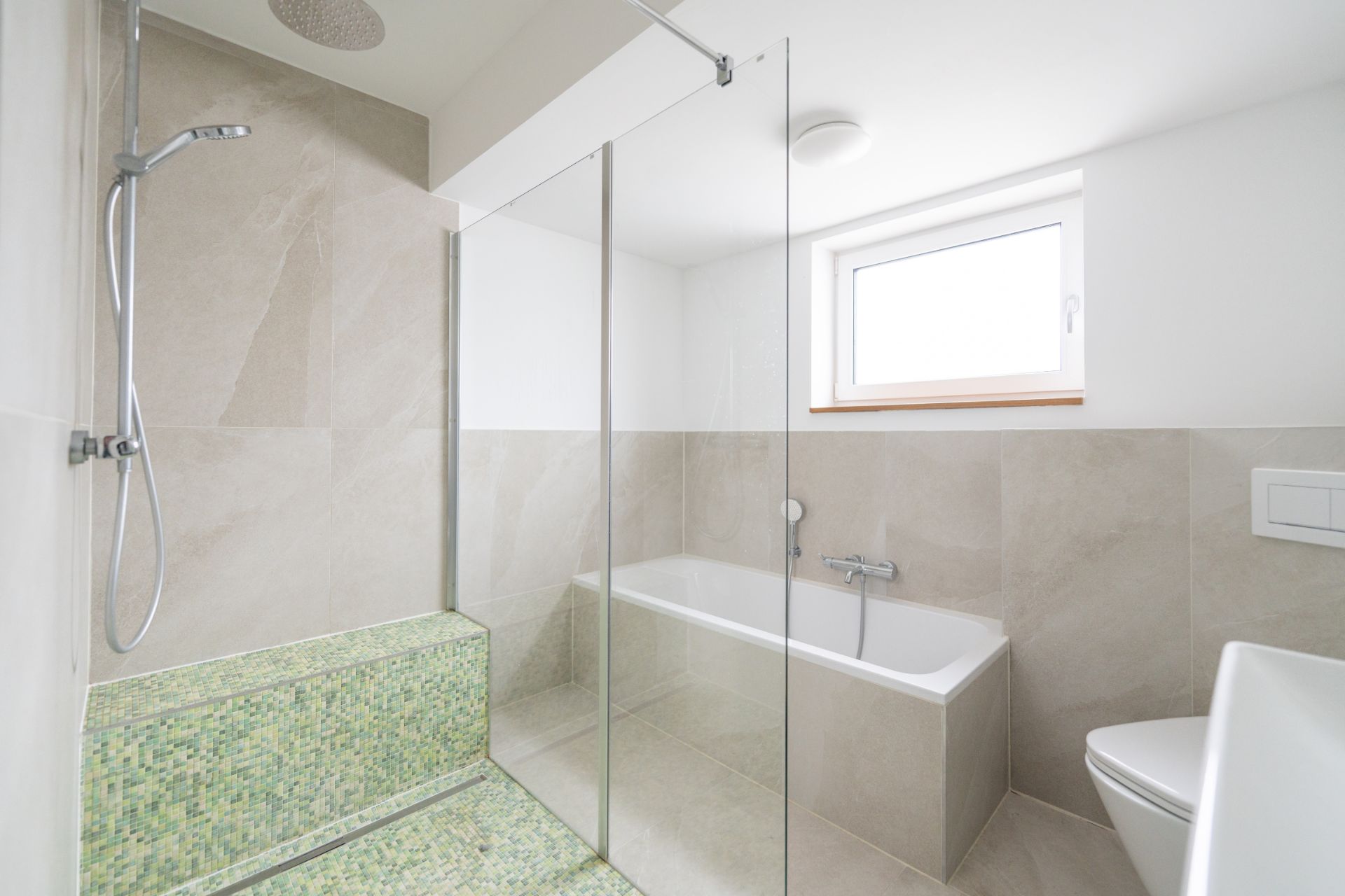 Modernes Badezimmer mit Glasdusche, Badewanne, WC und Fenster.