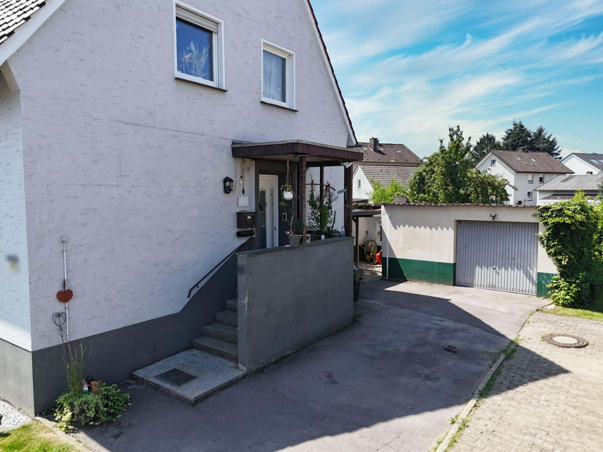 Zweistöckiges Wohnhaus mit kleinem Eingangsbalkon und Garage auf dem Grundstück.