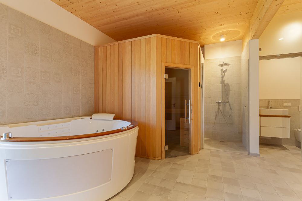 Modernes Badezimmer mit Whirlpool, Holzsauna, ebenerdiger Dusche und Waschtisch.