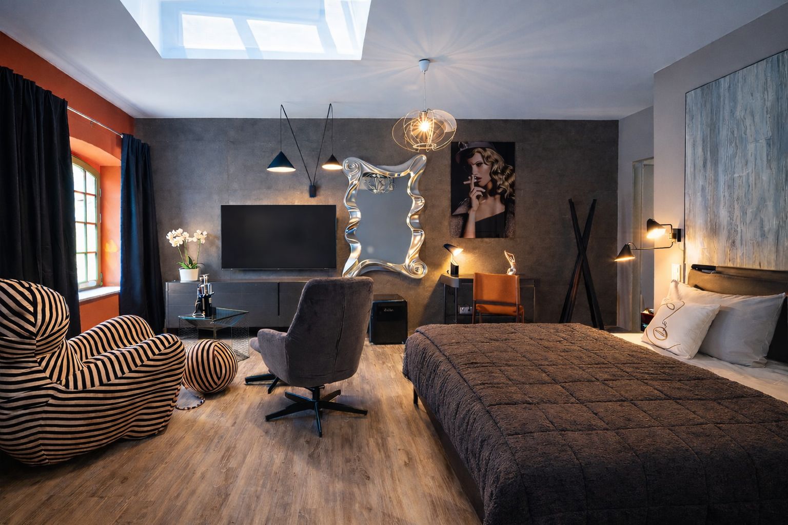 Modernes Schlafzimmer mit Doppelbett, TV, Schreibtisch, Designerstuhl und großem Fenster.
