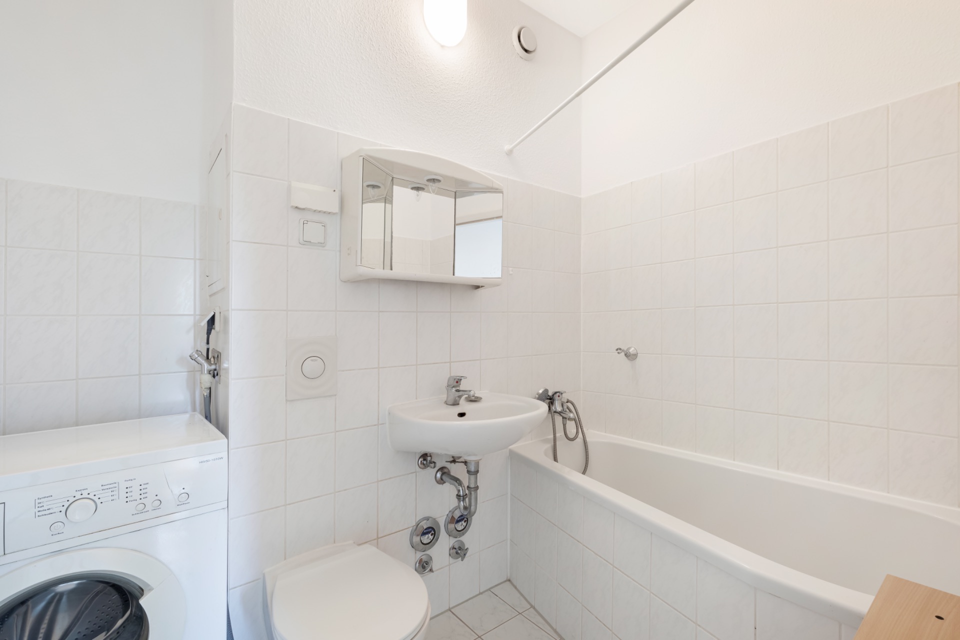 Helles Badezimmer mit Badewanne, Waschbecken, Toilette und Waschmaschine.