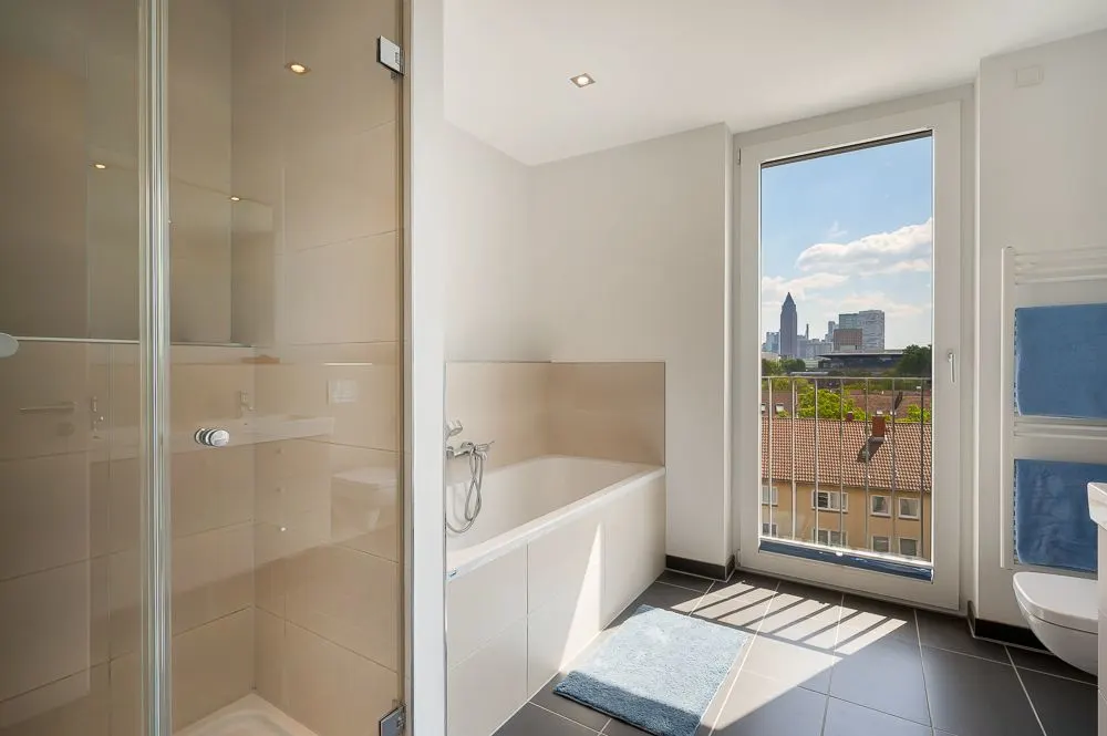 Modernes Badezimmer mit Dusche, Badewanne und großem Fenster mit Stadtblick.