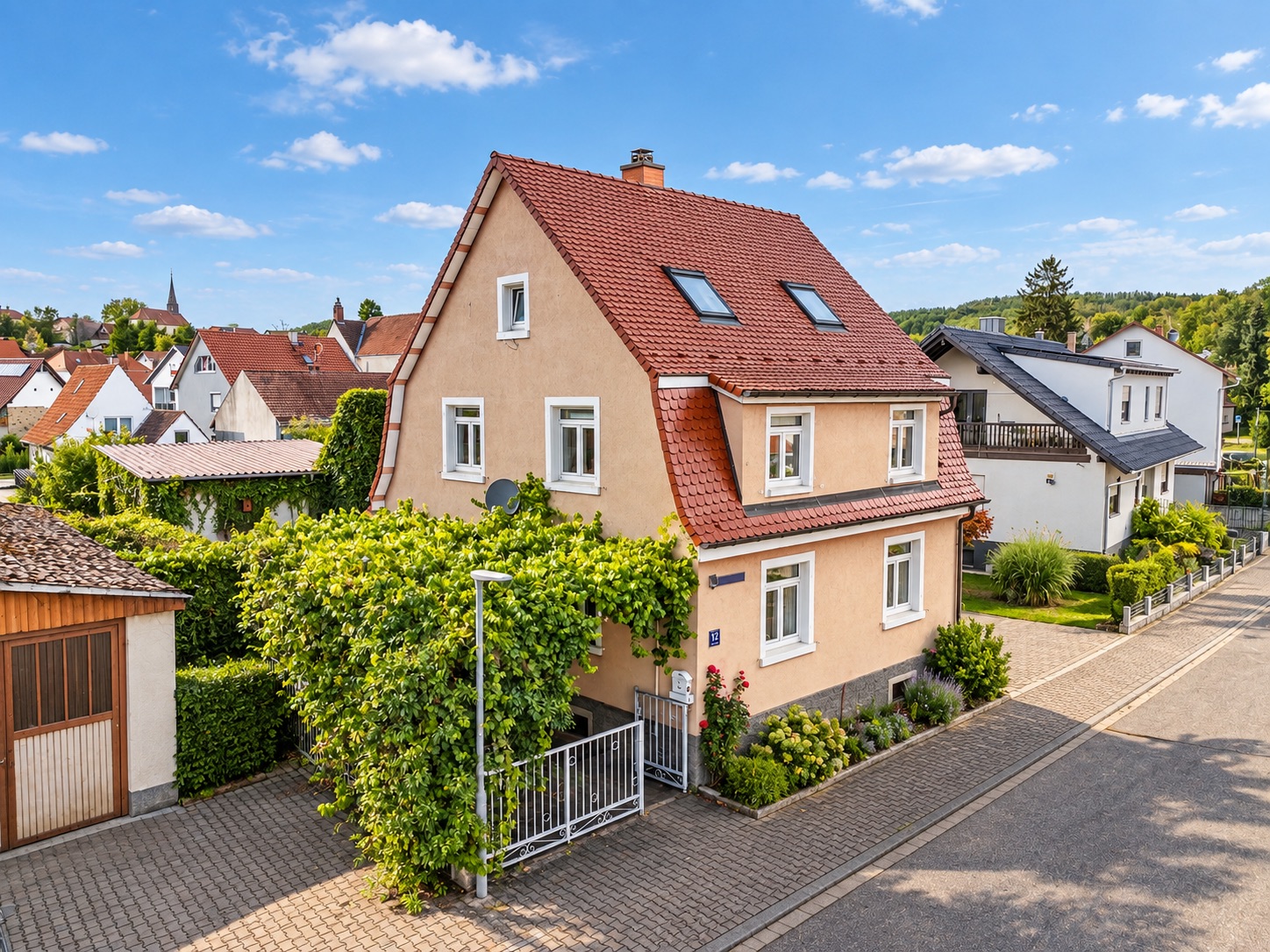Zweistöckiges Einfamilienhaus mit rotem Satteldach und kleinem Garten in ruhiger Wohnstraße.