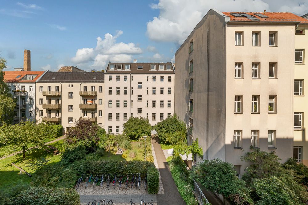 Blick auf einen grünen Innenhof mit Fahrrädern und umgebenden Wohnhäusern bei Tageslicht.