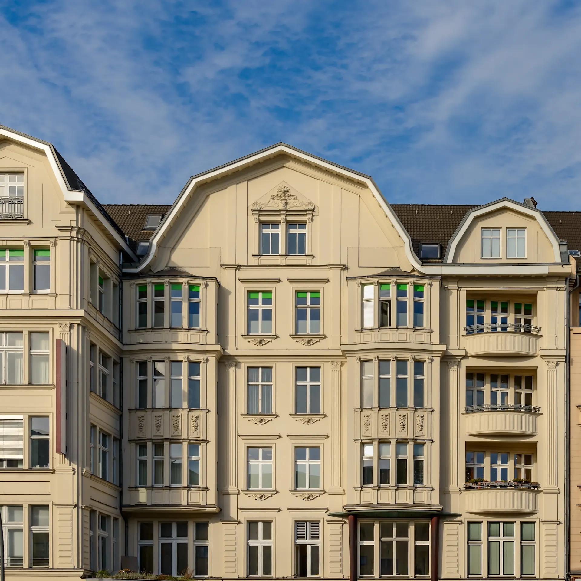 Fassade eines mehrstöckigen Wohnhauses mit vielen Fenstern und Balkonen.