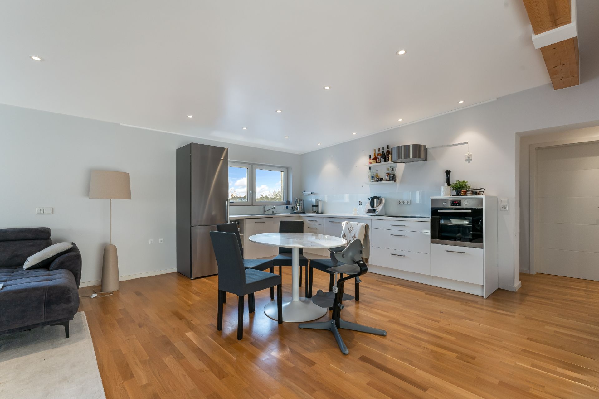 Moderne Wohnküche mit Esstisch, Stühlen, Sofa und Holzfußboden.