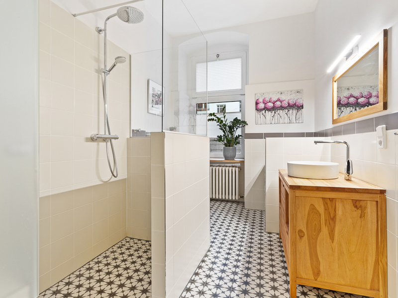 Modernes Badezimmer mit begehbarer Dusche, Holzwaschtisch und dekorativem Fliesenboden.