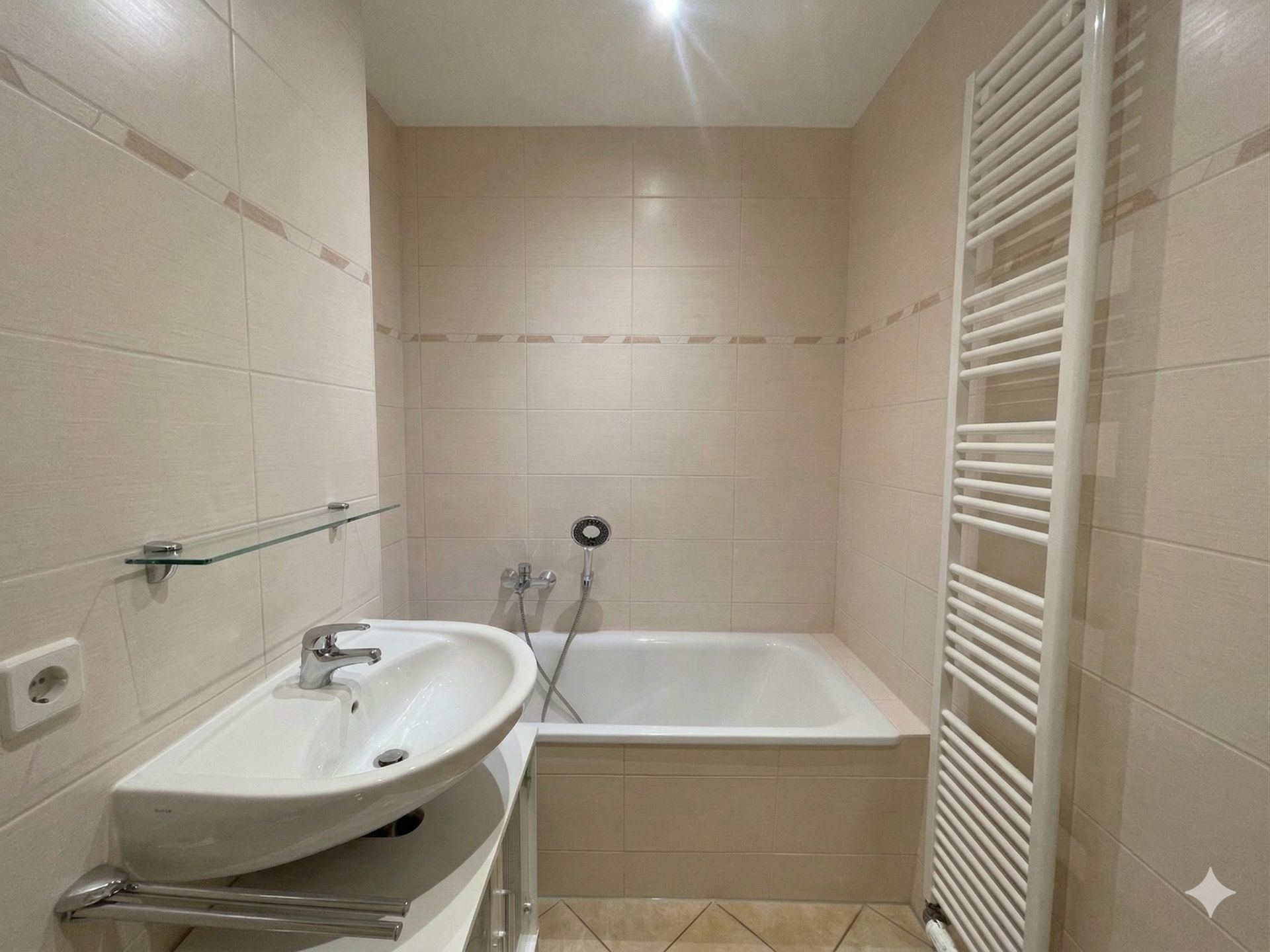 Badezimmer mit Waschbecken, Badewanne und Handtuchheizkörper.