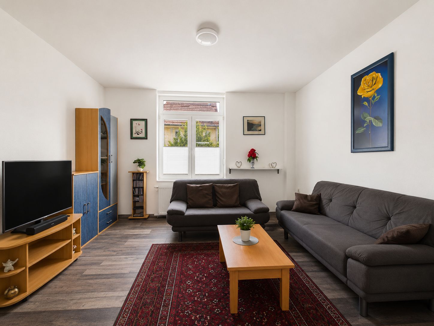 Wohnzimmer mit zwei Sofas, Teppich, Couchtisch, Fernseher und Wandbildern.