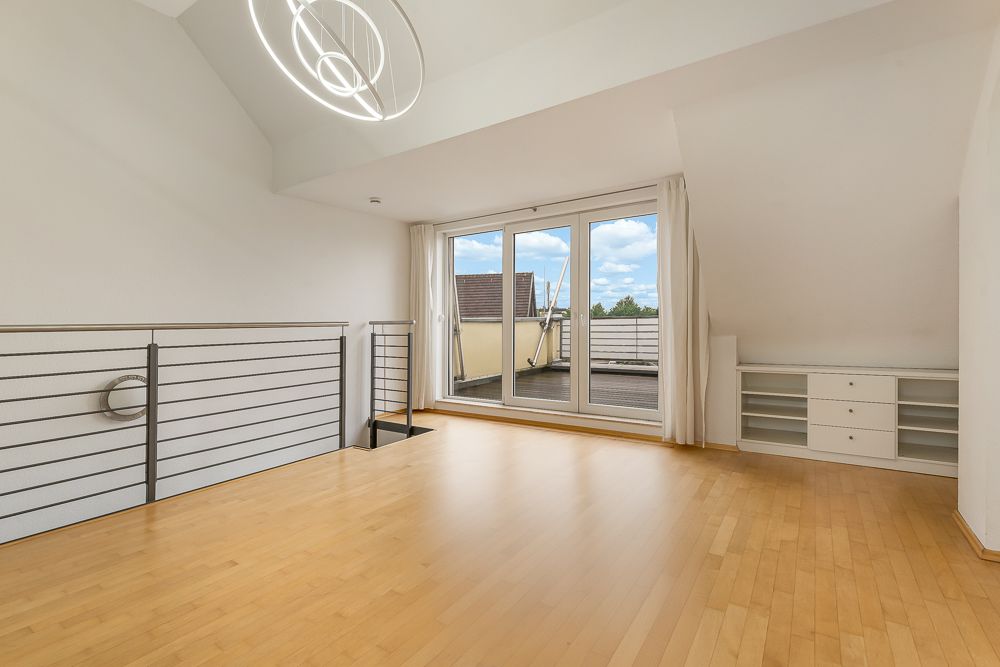 Heller Raum mit Holzfußboden, moderner Lampe, Einbauschrank und Zugang zu einem Balkon.