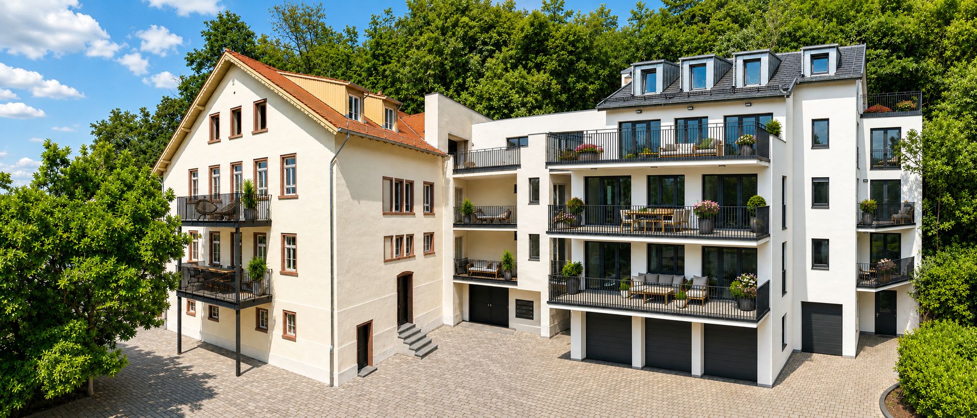 Zwei moderne Wohngebäude mit Balkonen, großen Fenstern und Garagen vor einem bewaldeten Hintergrund.