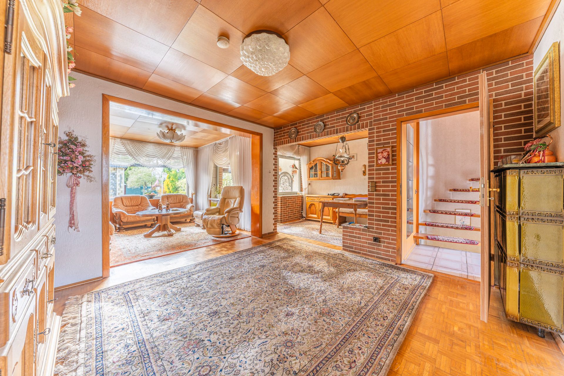 Wohnzimmer mit Teppichboden, Holzmöbeln und Zugang zu Essbereich, Sitzecke und Treppe.