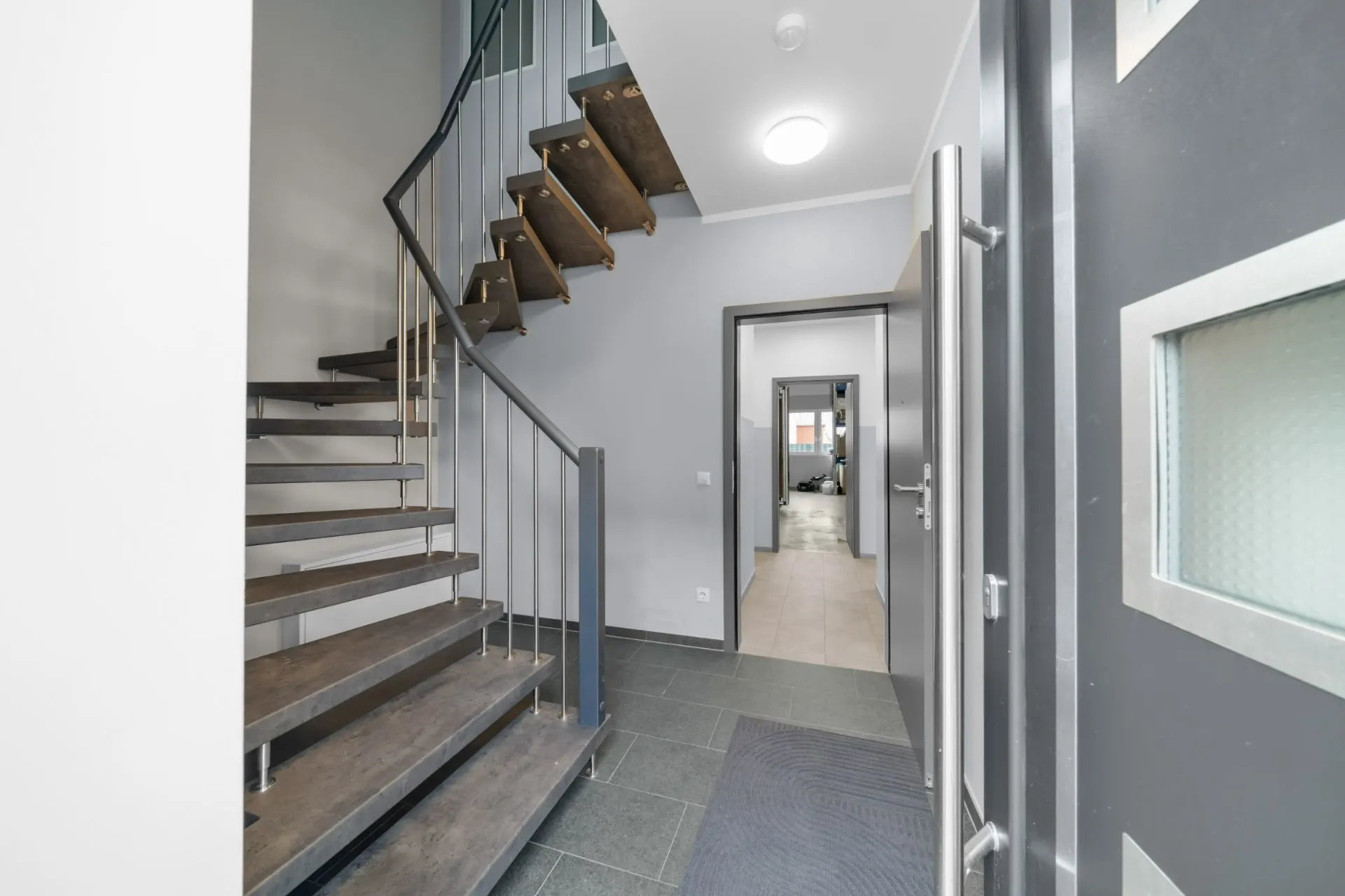 Eingangsbereich mit offener Treppe und Flur in einem Wohnhaus.