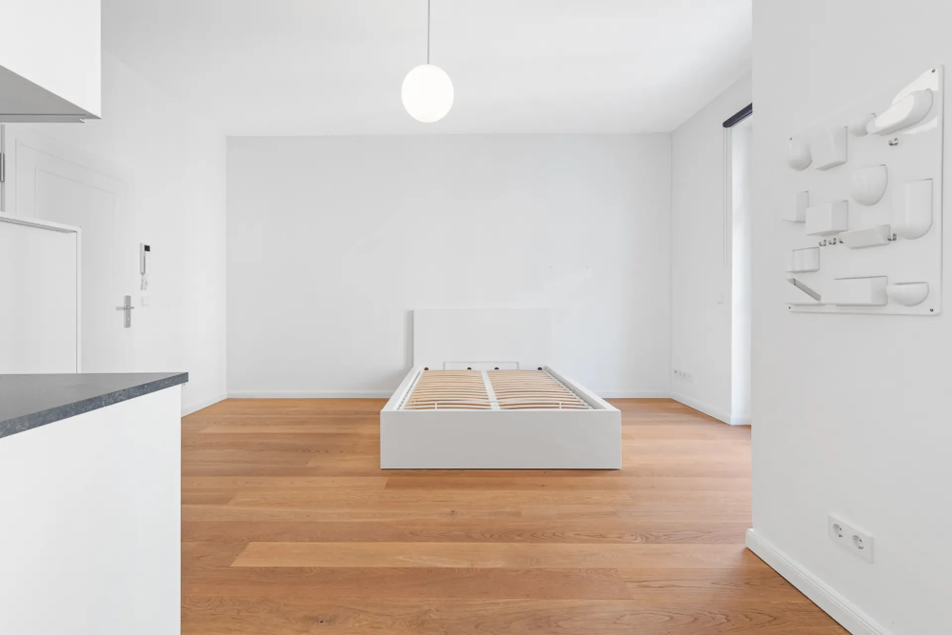 Helles Schlafzimmer mit Holzfußboden und weißem Bettgestell ohne Matratze.