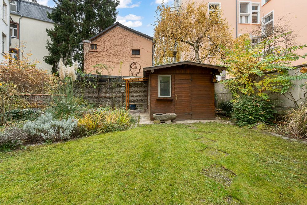 Garten mit Rasenfläche, Pflanzen und einem kleinen Holzhaus in Wohnumgebung.