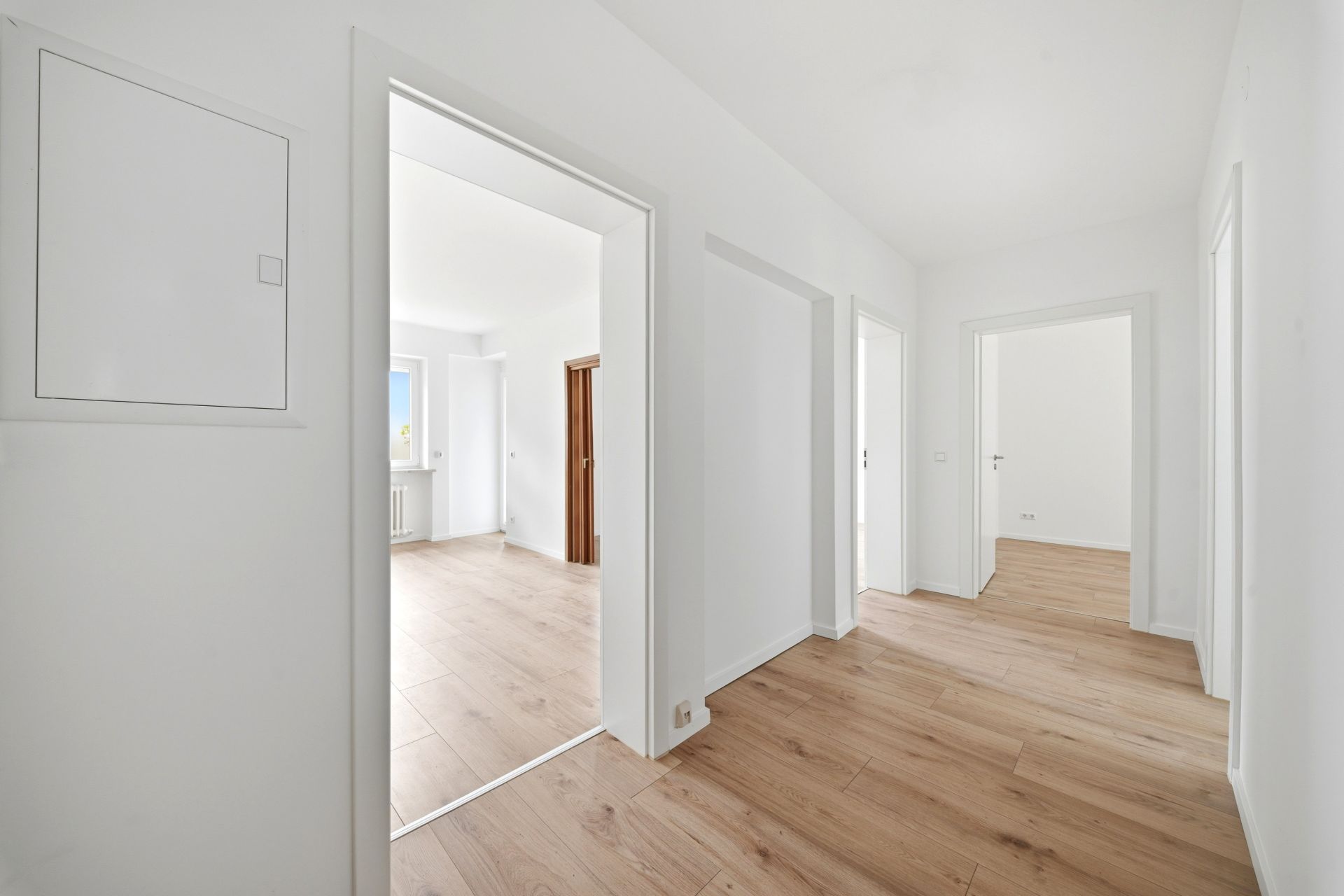 Heller Flur mit Holzboden und offenen Türen zu mehreren Zimmern in einer Wohnung.