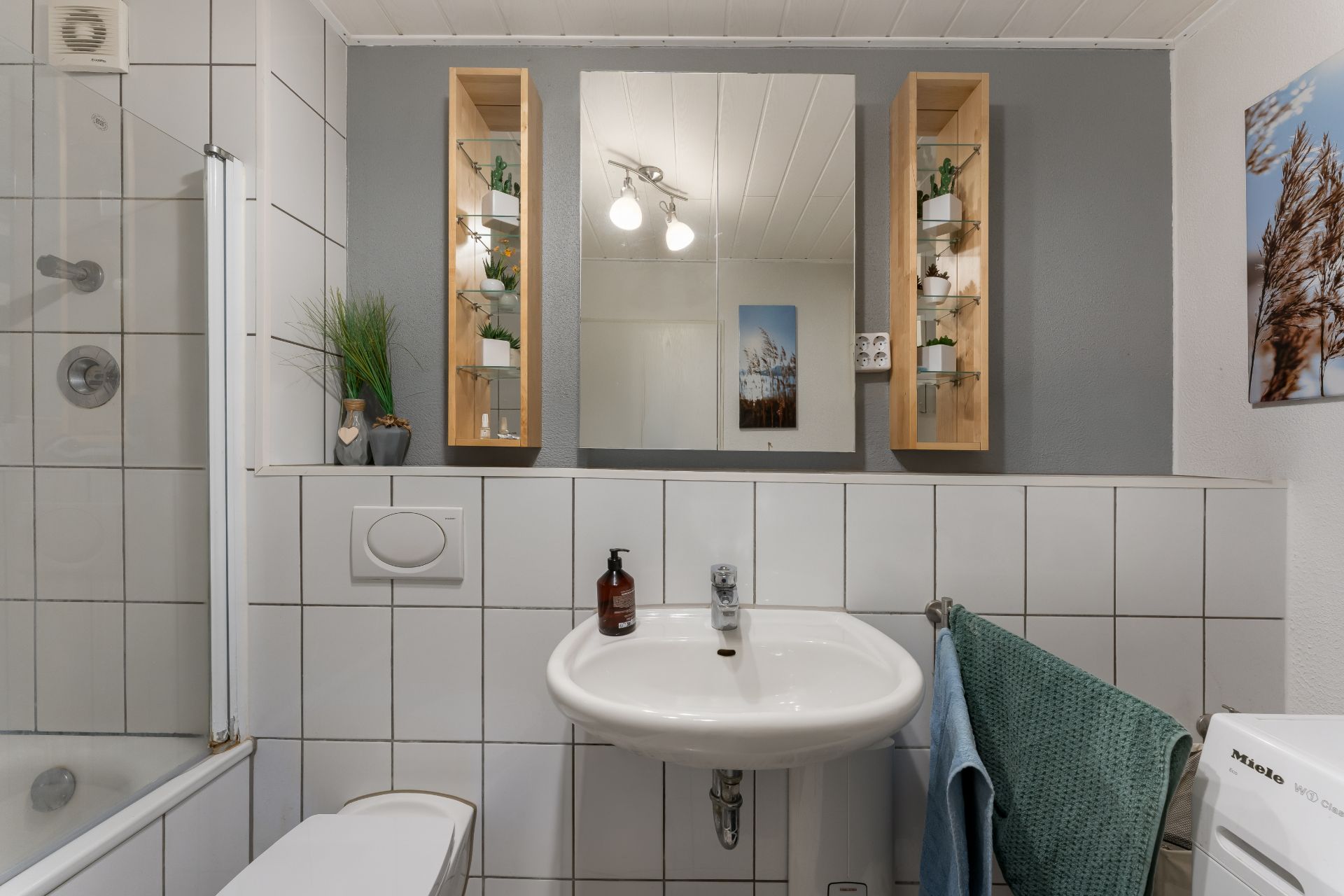 Modernes Badezimmer mit Waschbecken, Spiegel, Wandregalen und Handtuch.