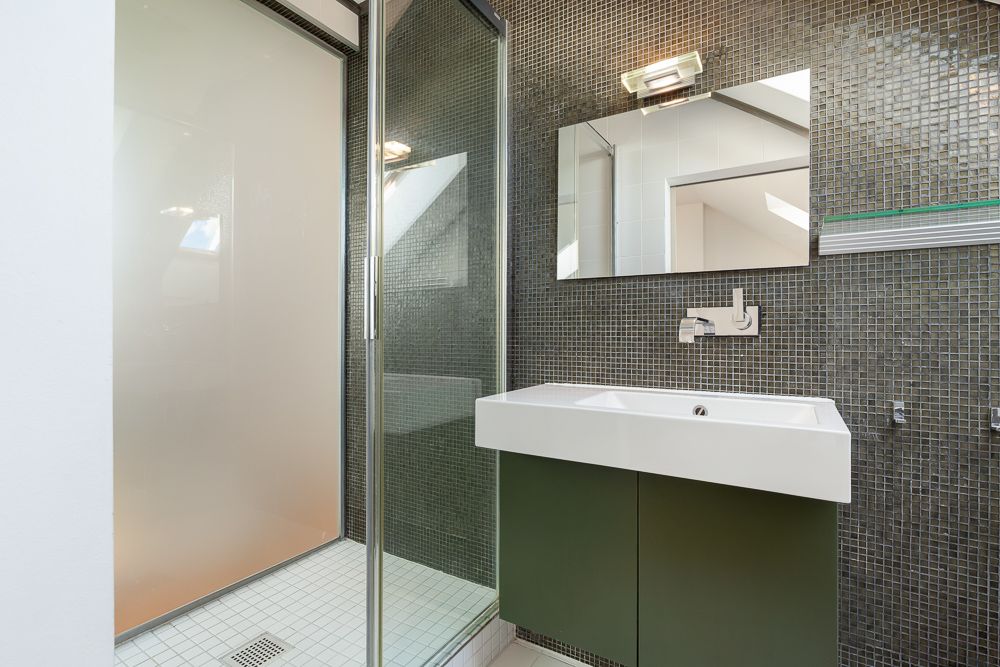 Modernes Badezimmer mit Glasdusche, Spiegel und Waschbecken mit Unterschrank.