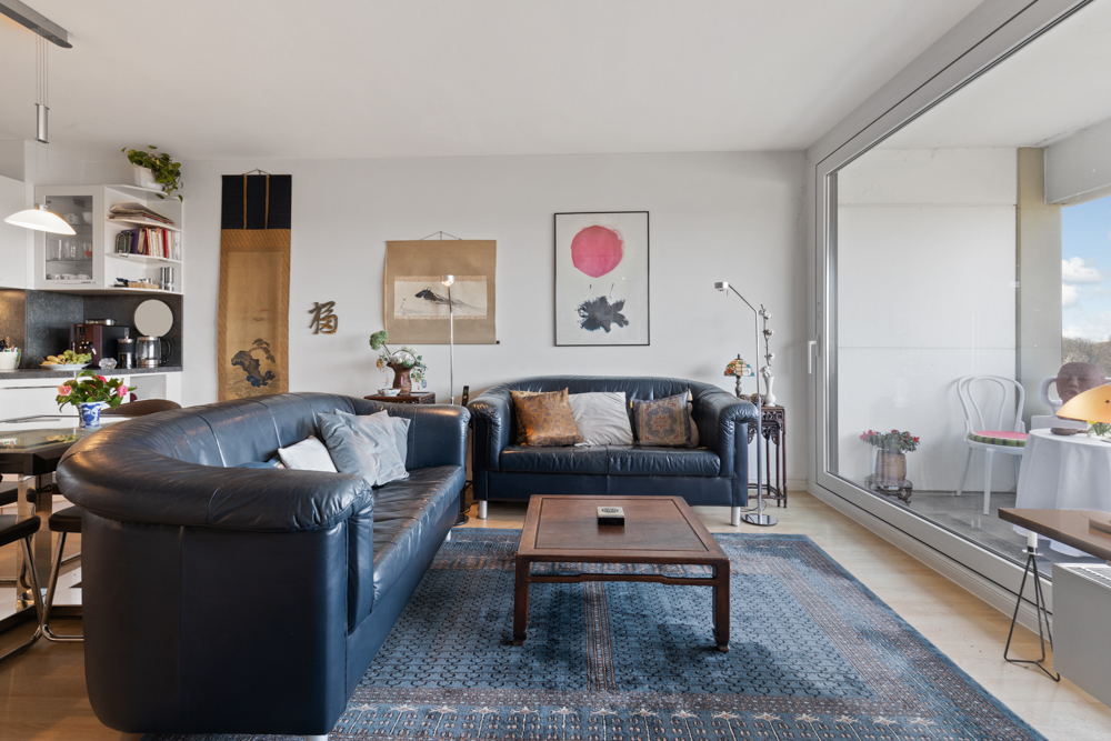 Modernes Wohnzimmer mit zwei blauen Ledersofas, Couchtisch und großer Fensterfront.