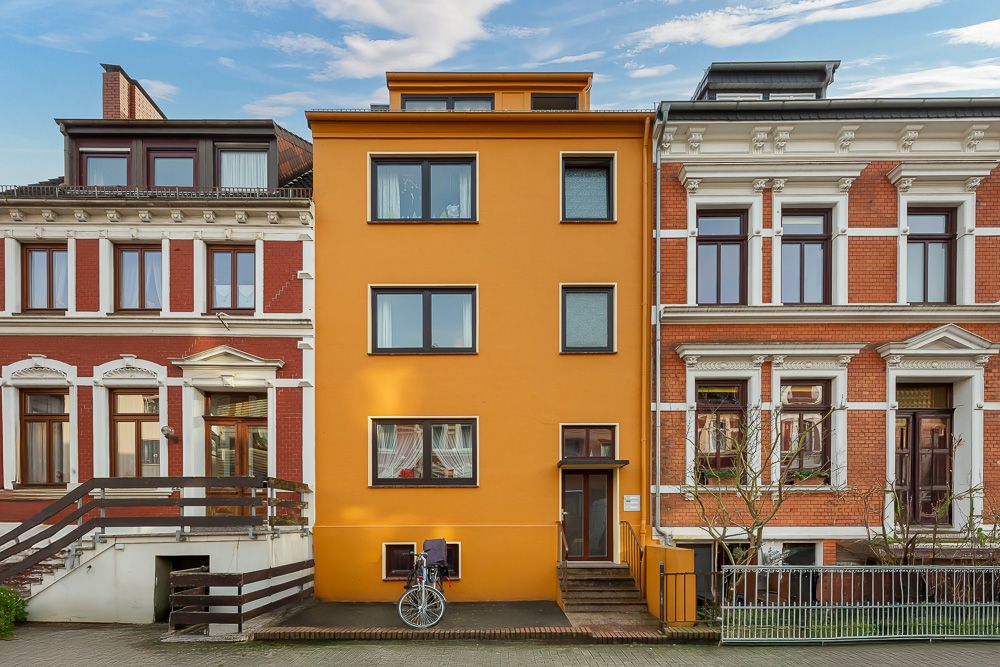 Orange Wohnhaus mit mehreren Fenstern und einem Fahrrad vor dem Eingang.