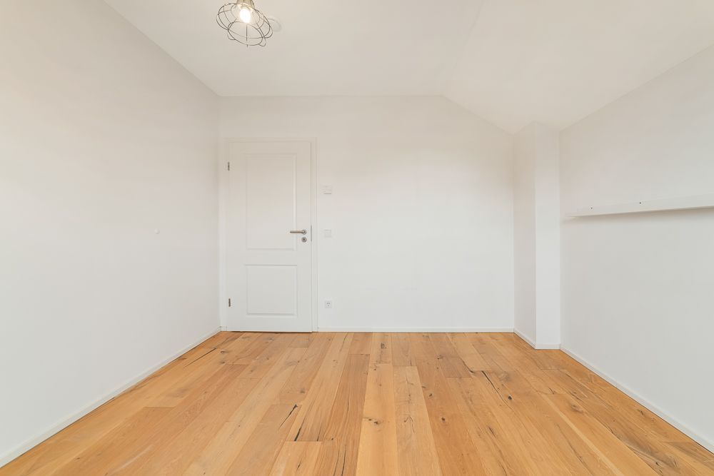 Leerer Raum mit weißer Tür, Holzfußboden und weiß gestrichenen Wänden.
