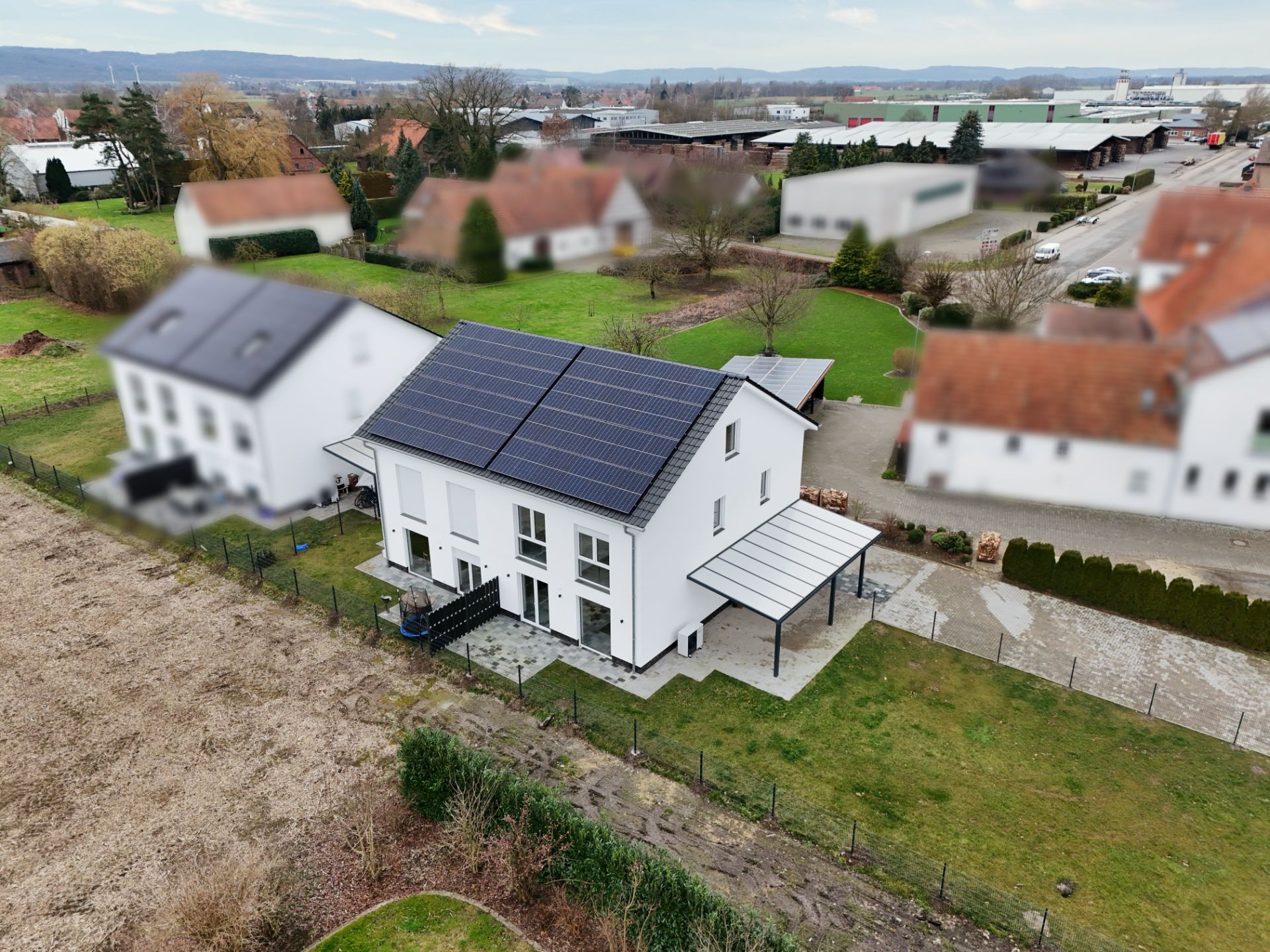 Modernes Wohnhaus mit Solaranlage auf dem Dach und überdachter Terrasse im Garten.