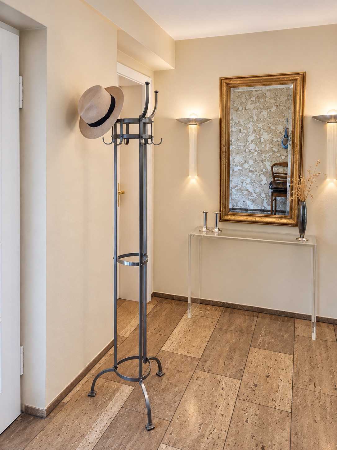 Flur mit Garderobenständer und Hut, Wandspiegel und Glas-Konsole mit Dekoration.