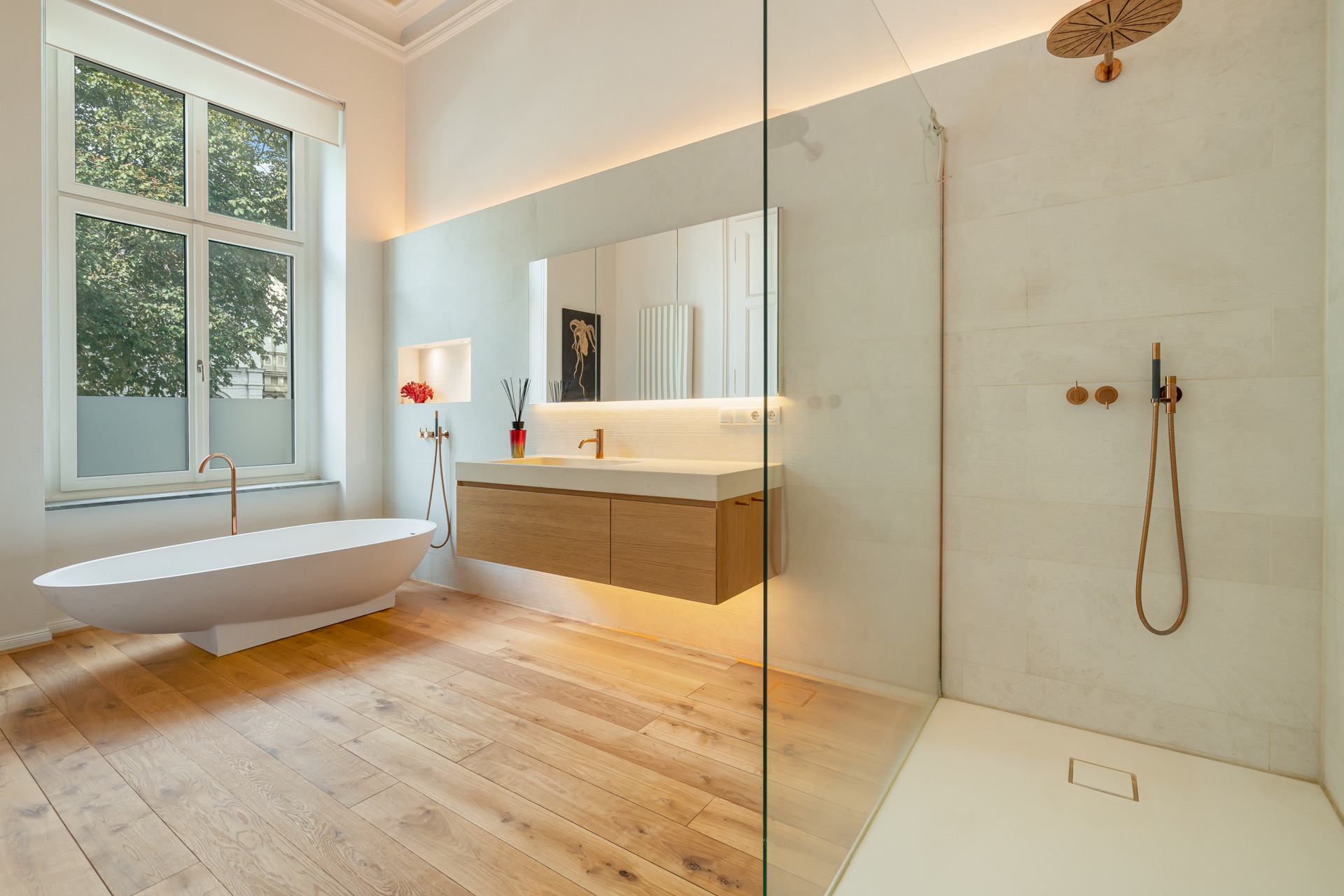 Helles Badezimmer mit freistehender Badewanne, Holzfußboden und großer begehbarer Dusche.
