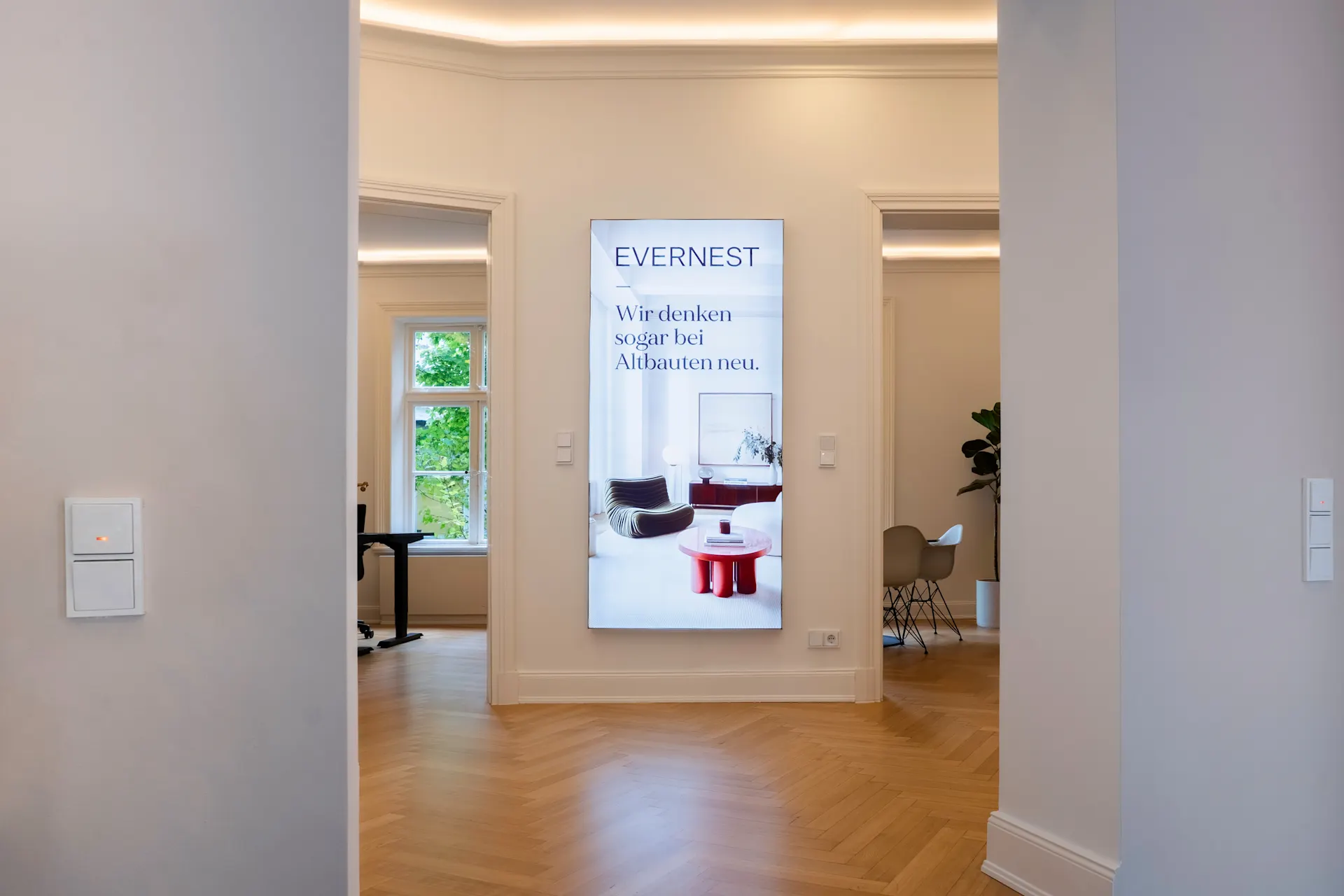 Heller Flur mit Parkettboden, beleuchtetem Deckenrand und großem Wandbild in einem Wohnhaus.
