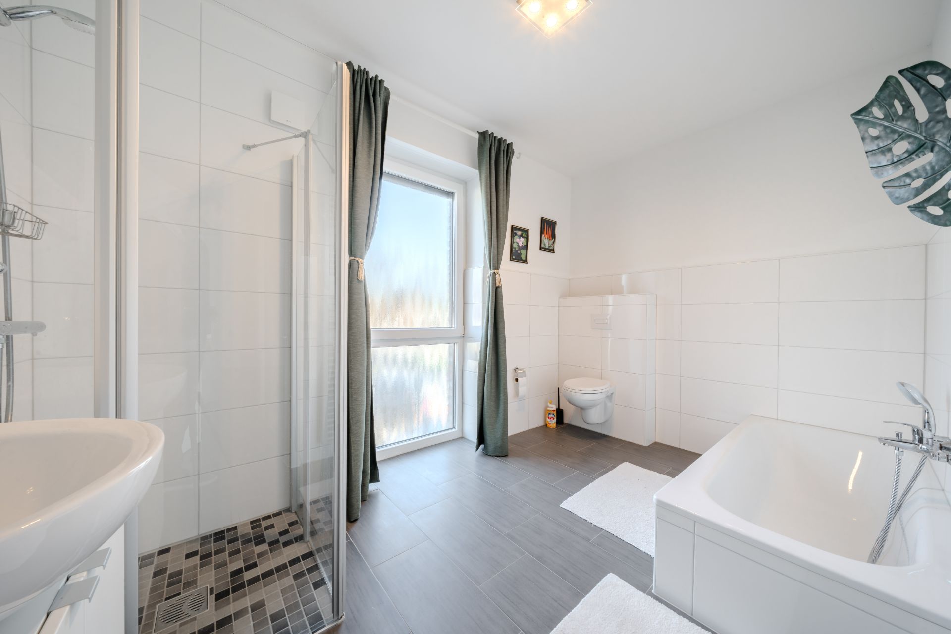 Modernes Badezimmer mit Dusche, Badewanne, WC, Waschbecken und Fenster mit Vorhängen.
